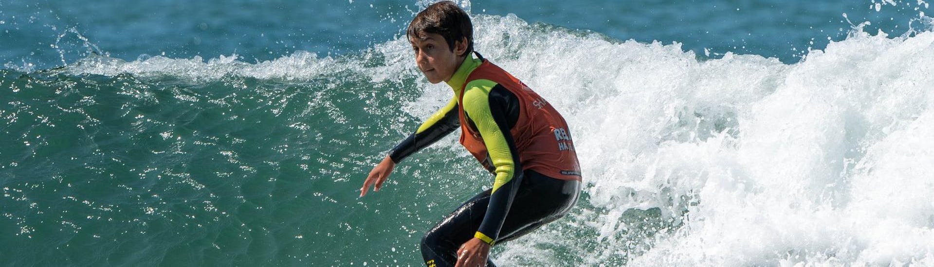 Under the guidance of an experienced surf instructor from Surfaventura, a boy is fully focused on riding his first wave during the surfing lessons on Matosinhos Beach.