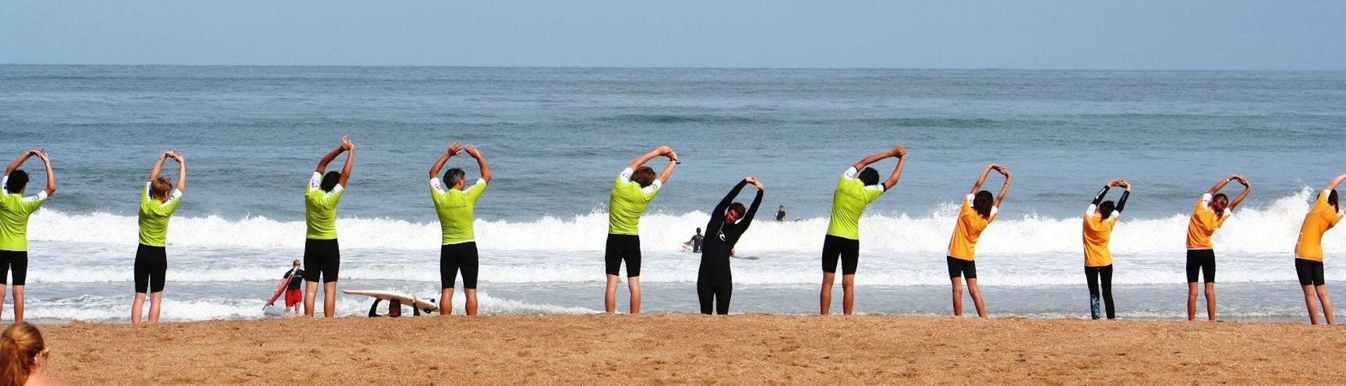 Les surfeurs s'échauffent sur la plage avant le début de leur Cours de surf collectif "À la carte" sur la Plage de Marinella à Anglet avec l'école de surf Le Club de la Glisse.
