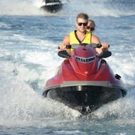 A couple has rented a powerful jet ski from Crazy Sports at Agios Georgios and is exploring the volcanic landscape of Santorini.