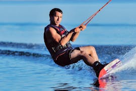 Un homme se concentre sur le wakeboard à Santorin tout en étant remorqué par un bateau à moteur de Crazy Sports.