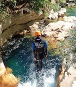 A participant of the River Trekking in Gorges du Loup for Young & Old tour with FunTrip is jumping into a beautiful pool of clear water.