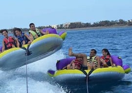 A group of friends is enjoying the thrilling ride on an inflatable boat towed by a motor boat from Crazy Sports.