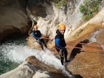 Two friends are abseiling down the canyon during their Canyoning in the Gours du Ray Canyon - Aquatic tour with FunTrip.