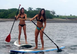 Two girls practising paddle surf with our Stand Up Paddle Board Rental in San José - Ibiza with Take Off Ibiza.