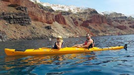 During a sea kayak tour, a couple is paddling with a professional kayak guide from Santorini Sea Kayak around the magical city of Santorini.