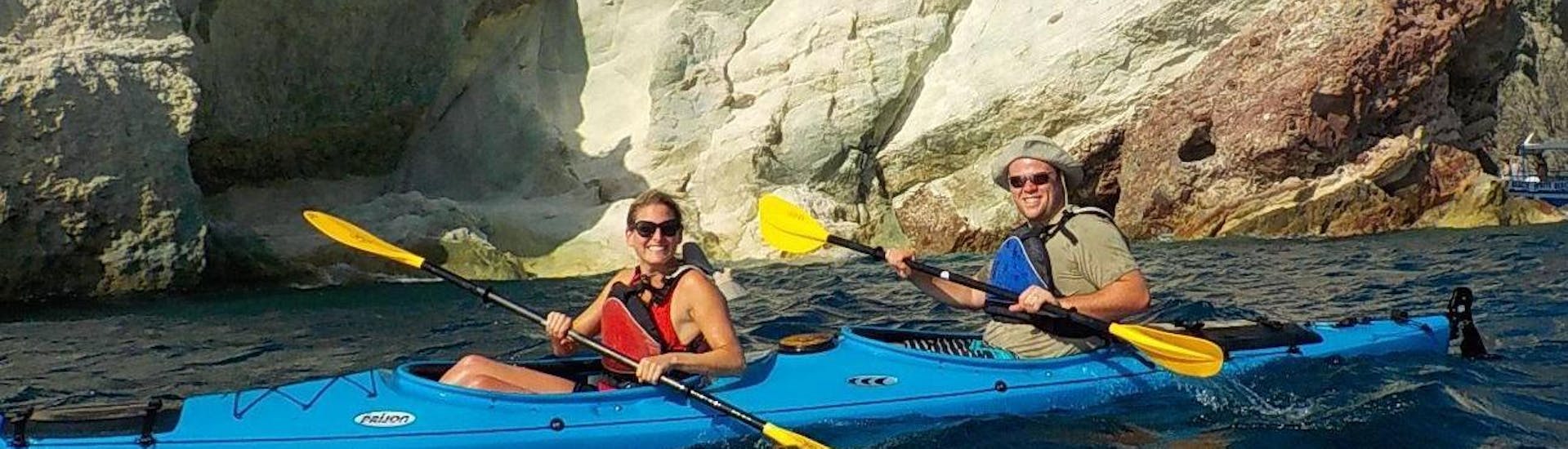 Led by a local certified kayak guide from Santorini Sea Kayak, a couple is paddling along a rocky coast of Santorini during a sea kayak tour.