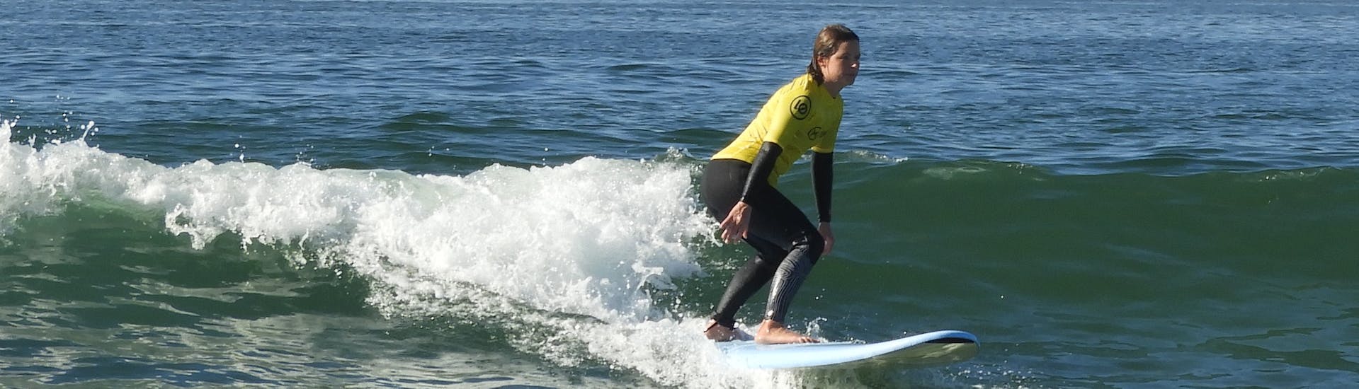 Una niña está aprendiendo a surfear durante sus Clases Particulares de Surf en Matosinhos con Linha De Onda Surfing School Matosinhos.