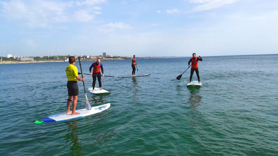 A group of friends is having fun whilst balancing on a SUP during the private Stand Up Paddle lessons organised by Surfaventura.