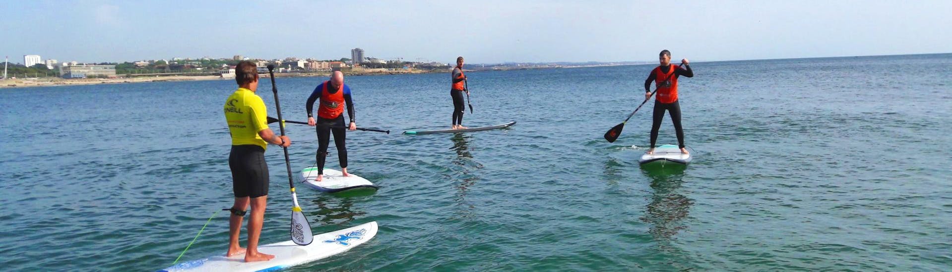 Un grupo de amigos se divierte mientras intentan encontrar el equilibrio arriba de una tabla de SUP durante su curso privado de Paddle Surf organizado por Surfaventura.