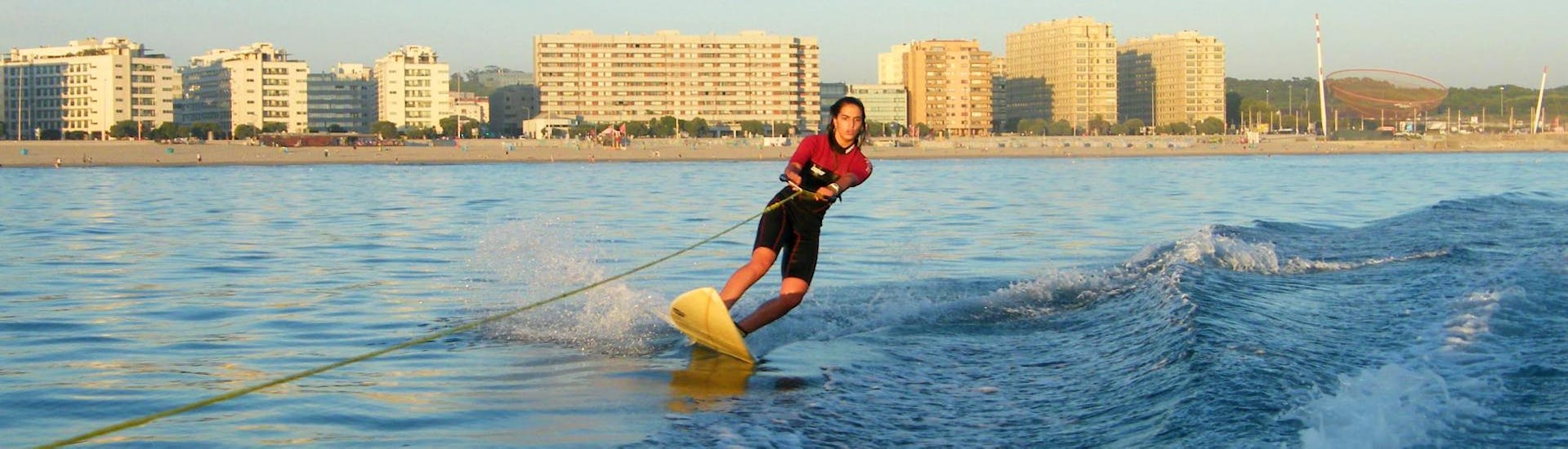 During the private wakeboard & wakesurf lessons, a woman is enjoying wakesurfing under the supervision of a qualified instructor from Surfaventura.