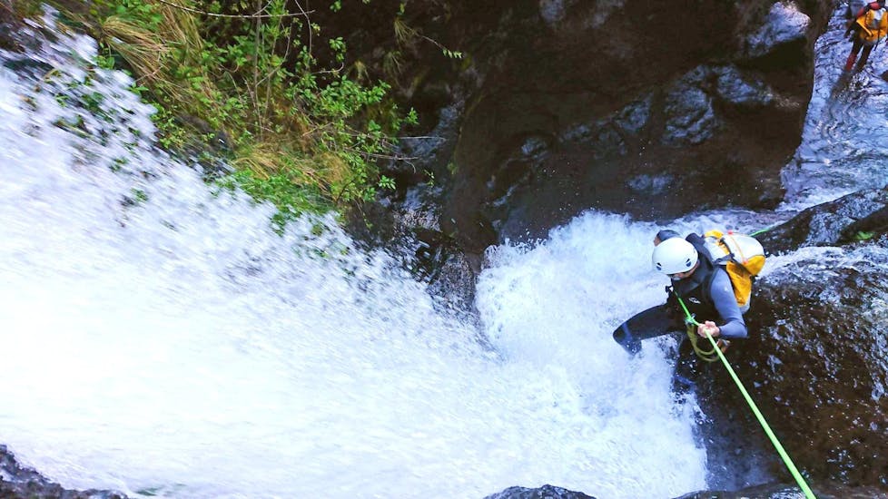 Beim Canyoning für Sportliche in Madeira mit Epic Madeira seilt sich ein Teilnehmer mutig über einen tosenden Wasserfall ab.