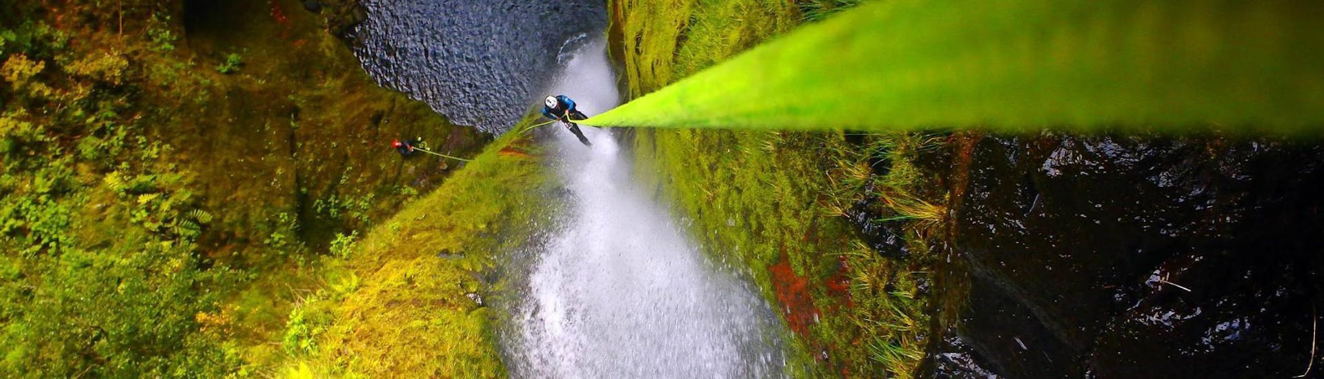 Un partecipante al canyoning avanzato di Madeira si cala in corda doppia lungo una cascata con l'aiuto di una guida esperta di Epic Madeira.