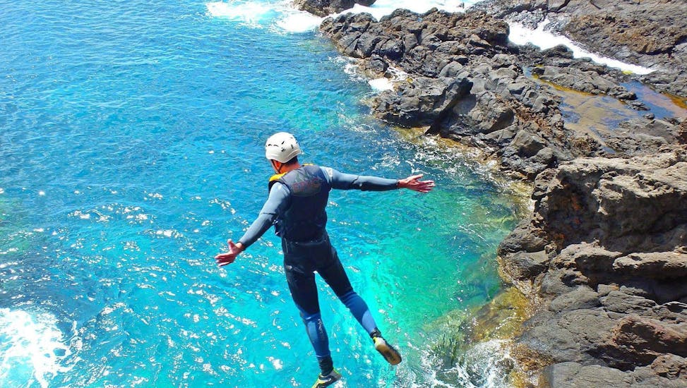 A participant of the Coasteering at Ponta de São Lourenço with Epic Madeira is jumping into the turquoise water of the ocean.