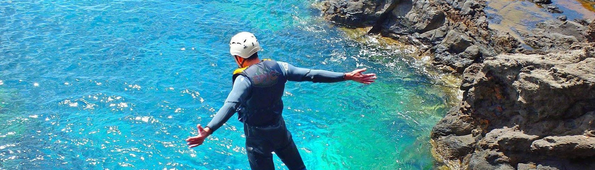 A participant of the Coasteering at Ponta de São Lourenço with Epic Madeira is jumping into the turquoise water of the ocean.