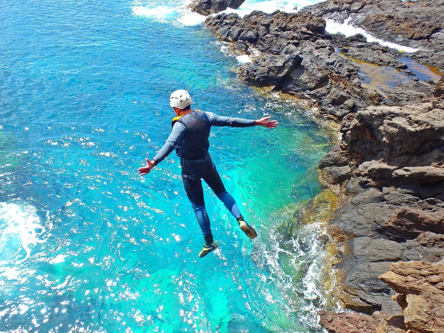 Un partecipante al Coasteering a Ponta de São Lourenço con Epic Madeira si tuffa nelle acque turchesi dell'oceano.