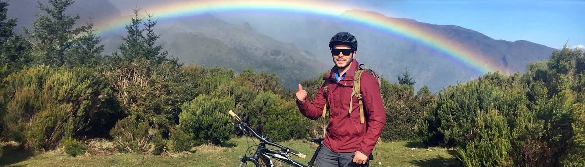During the Mountain Bike Adventure Ride at Pico do Arieiro organized by Epic Madeira, a participant is stopping to pose for a picture with a rainbow.