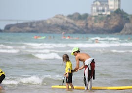 A girl is having private surfing lessons on the Marbella Beach with her instructor of the eco surf school in Biarritz.