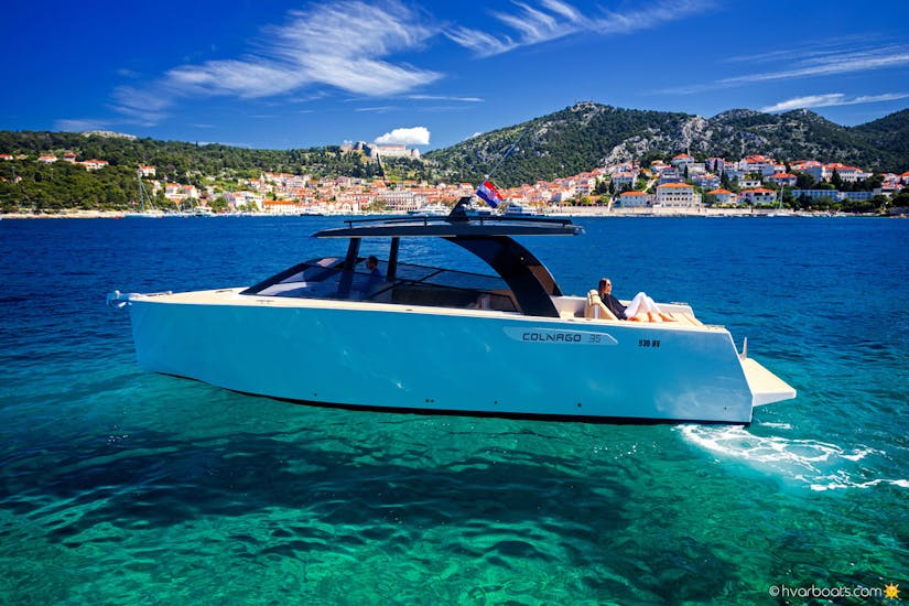 Picture of the luxury boat Colnago 33 with woman laying in the back and the background of the coast of Hvar.