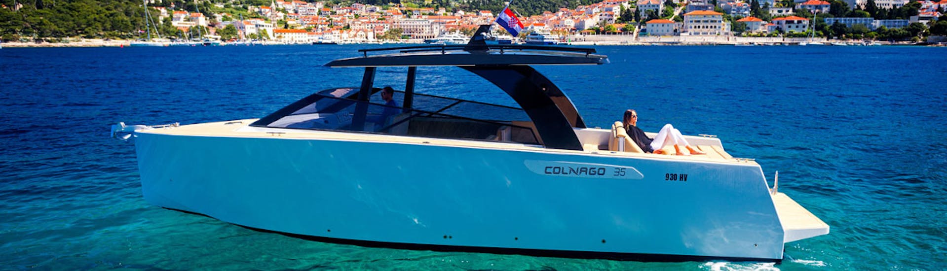 Picture of the luxury boat Colnago 33 with woman laying in the back and the background of the coast of Hvar.