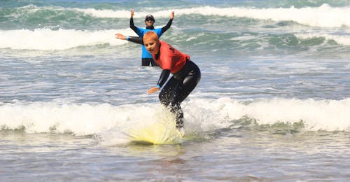 Cours de surf pour Débutants (dès 7 ans)  jusqu'à 6 personnes avec Algarve Adventure Un jeune surfeur prenant sa première vague lors de ses cours de surf pour Débutants avec Algarve Adventure.