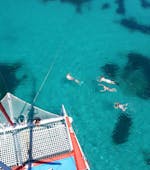 Die Tourteilnehmer baden sich im glasklaren Wasser während der Segelkatamaran Tour mit Schnorcheln, Paella & Getränken, organisiert von Robinson Boat Trips.
