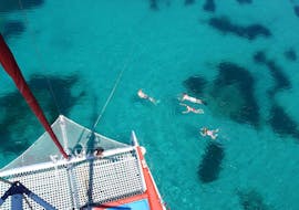 Die Tourteilnehmer baden sich im glasklaren Wasser während der Segelkatamaran Tour mit Schnorcheln, Paella & Getränken, organisiert von Robinson Boat Trips.