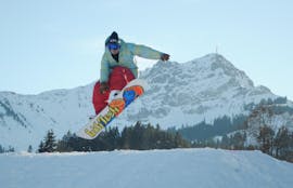 Un snowboardeur dans les airs durant les Cours de snowboard pour Enfants & Adultes pour Débutants avec l'école de ski avec l'école de ski Snow Sports School Eichenhof St. Johann.