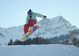 A snowboarder in the air during the Snowboarding Lessons for Kids & Adults for Beginners with the Snow Sports School Eichenhof St. Johann.