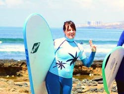 Una donna posa davanti alla telecamera e si prepara a iniziare le sue lezioni di surf per principianti con la Ocean Life Surf School.