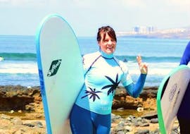 A woman is posing in front of the camera and prepared to begin her beginner surf lessons with Ocean Life Surf School.