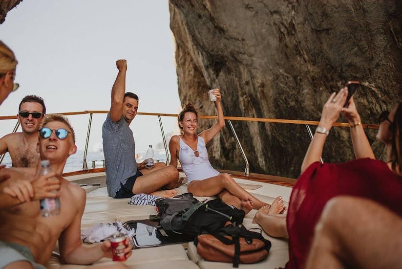 Mensen die op een boot liggen en drinken en juichen tijdens een Privé Boottocht rond het eiland Capri met Capitano Ago Costiera Amalfitana.