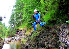 A participant jumps from a rock into a natural pool during the Sportive Canyoning Tour in the Schwarzwasserbach with The Over and Out - Bad Hindelang.