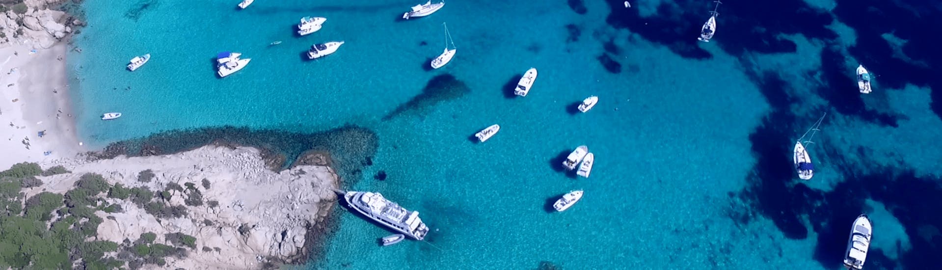 Alcune barche si avvicinano a una delle magnifiche spiagge della Sardegna durante il viaggio in barca da Palau all'arcipelago di La Maddalena.