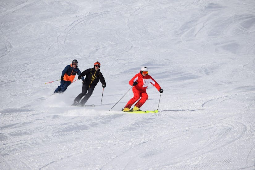 A ski instructor with two students going down the slope during private ski lessons for adults of all levels with ski school Westendorf.