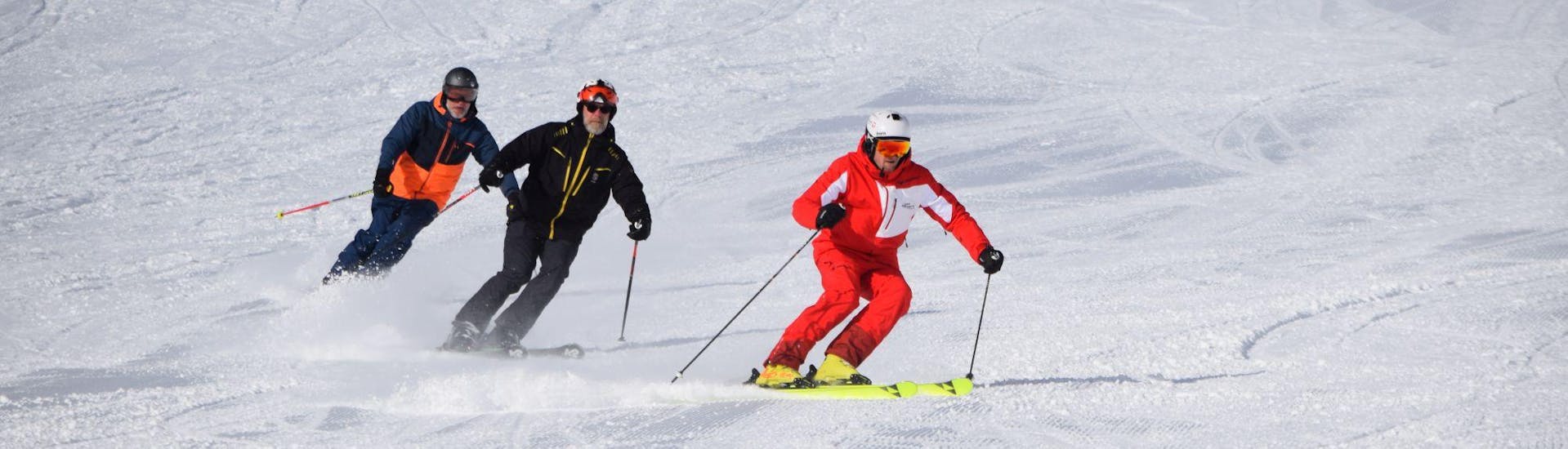 Een skileraar met twee leerlingen gaat de piste af tijdens privé-skilessen voor volwassenen van alle niveaus bij skischool Westendorf.