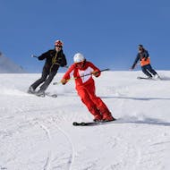 Een skileraar laat zijn leerlingen zien hoe ze moeten skiën tijdens privé skilessen voor volwassenen van alle niveaus bij skischool Westendorf.