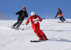 Een skileraar laat zijn leerlingen zien hoe ze moeten skiën tijdens privé skilessen voor volwassenen van alle niveaus bij skischool Westendorf.