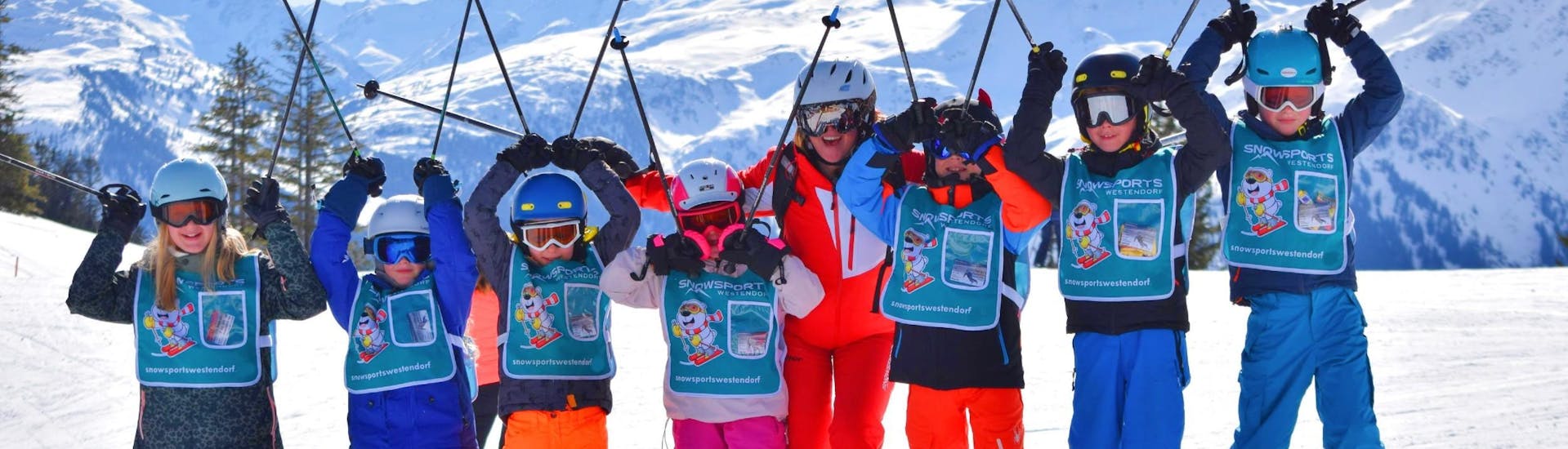 Eine Gruppe von Kindern jubelt während des Kinder-Skikurses (5-14 J.) für alle Levels mit der Skischule Snowsports Westendorf.