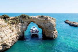 Pendant la balade en catamaran depuis Vilamoura vers les grottes de Benagil, les touristes passent sous une formation rocheuse à bord d'un catamaran moderne de Ocean Quest.