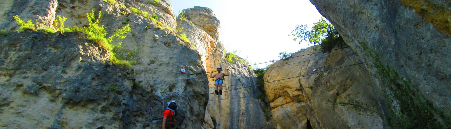 A man is crossing a gorge on a suspension bridge during his Via Ferrata in Ardèche - Pont du Diable with Geo Ardèche Canyon.