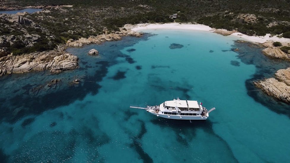A beautiful and spacious boat sails across the bay during the 4 Islands Boat Trip to La Maddalena Archipelago from Palau.