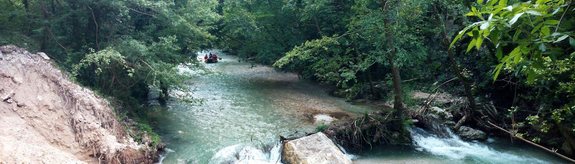 Lively river with a raft boat in the distance during the Classic Rafting on the River Corno with Rafting Nomad Vallo di Nera.