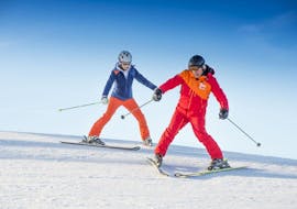 A woman is riding down a slope using the plough with her instructor during her Private Ski Lessons for All Ages & Levels with skischule Tritscher.