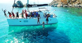 Friends are jumping into the crystal clear water during their Luxury Catamaran Cruise from Naxos with Snorkeling Breaks with Naxos Yachting.