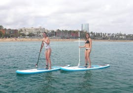 Two friends enjoying during a Stand Up Paddleboarding Lessons in Barcelona for Beginners with Moloka'i SUP Center Barceloneta.