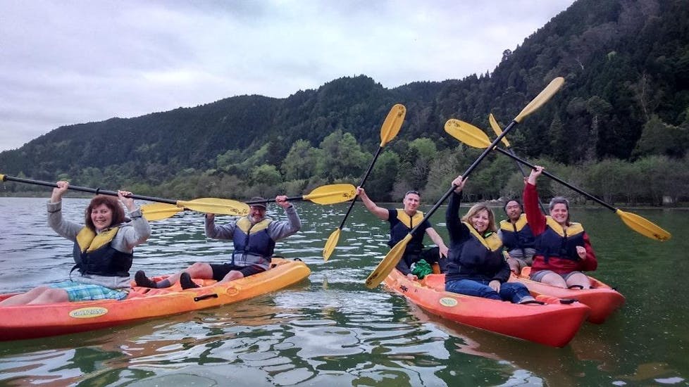 The group is cheering at the camera during the Canoeing in Lagoa das Furnas.