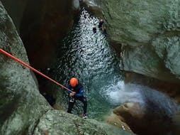 Een man die deelneemt aan Canyoning "Sensation" - Pont du Diable met Térreo Canyoning daalt af naar een grot.