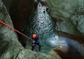 Een man die deelneemt aan Canyoning "Sensation" - Pont du Diable met Térreo Canyoning daalt af naar een grot.