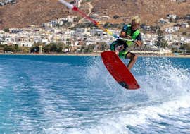 Wakeboarden op Saint George Strand in Naxos met Flisvos Watersports 1974 Naxose. Een persoon doet een sprong in het water met een wakeboard tijdens het wakeboarden op Saint George strand in Naxos met Flisvos Watersports 1974 Naxose.
