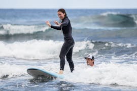 A girl is learning how to surf during a Surfing Lessons for Kids & Adults - All Levels with Black Sand Box Ponta Delgada.